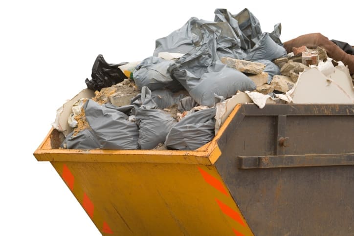 Blue construction debris container filled with rock and concrete rubble. Industrial garbage bin