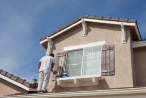 House painter painting the trim and shutters of home